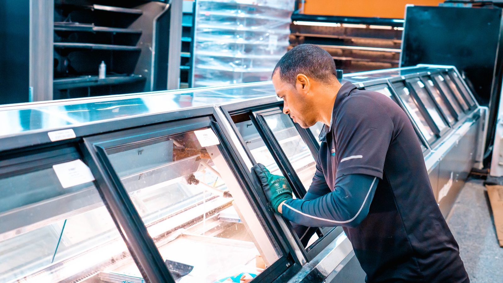 Technician working on open refrigerated display cases to improve energy efficiency